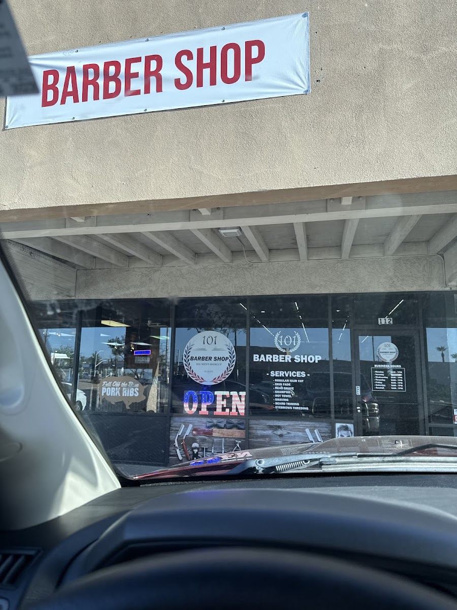 Storefront of 101 Barber Shop with a red Barber Shop banner above the windows