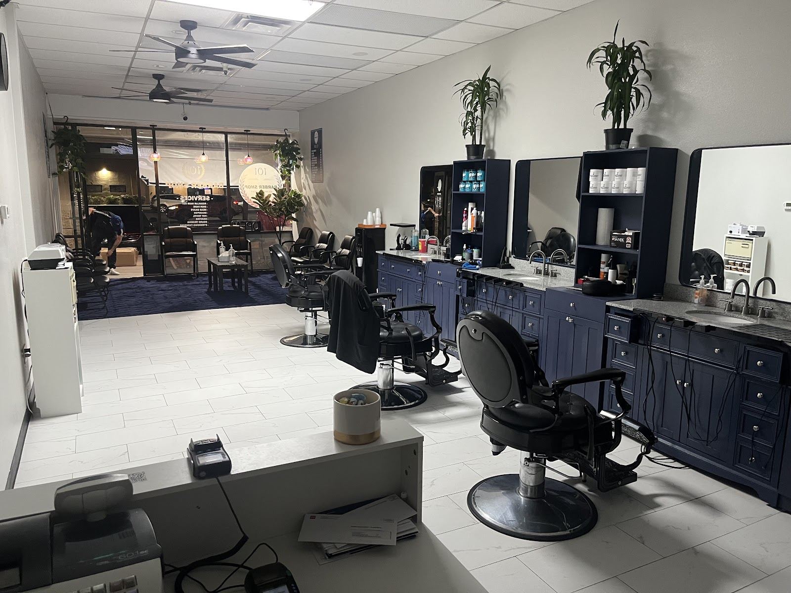 Inside 101 Barber Shop: black barber chairs lined up at navy blue stations with mirrors
