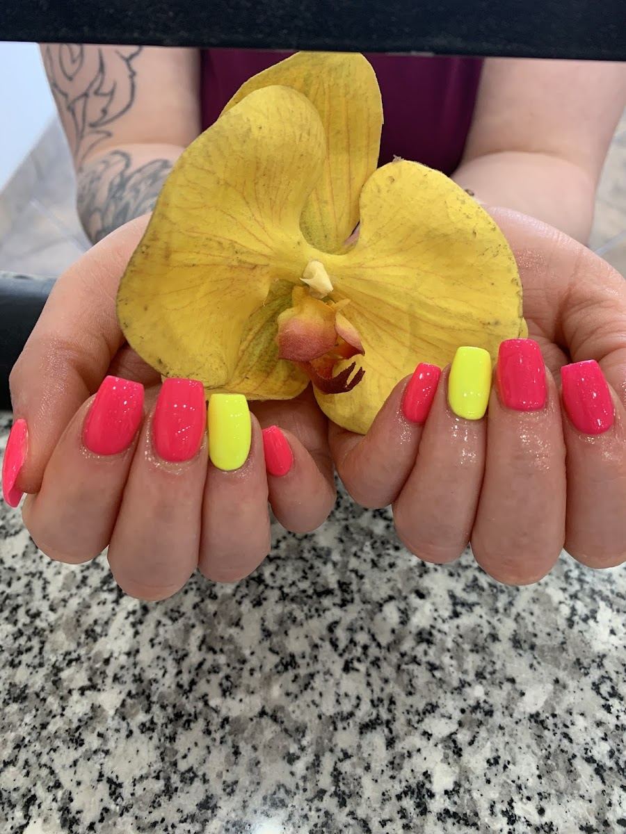Hands with coral and neon yellow square nails holding a yellow orchid