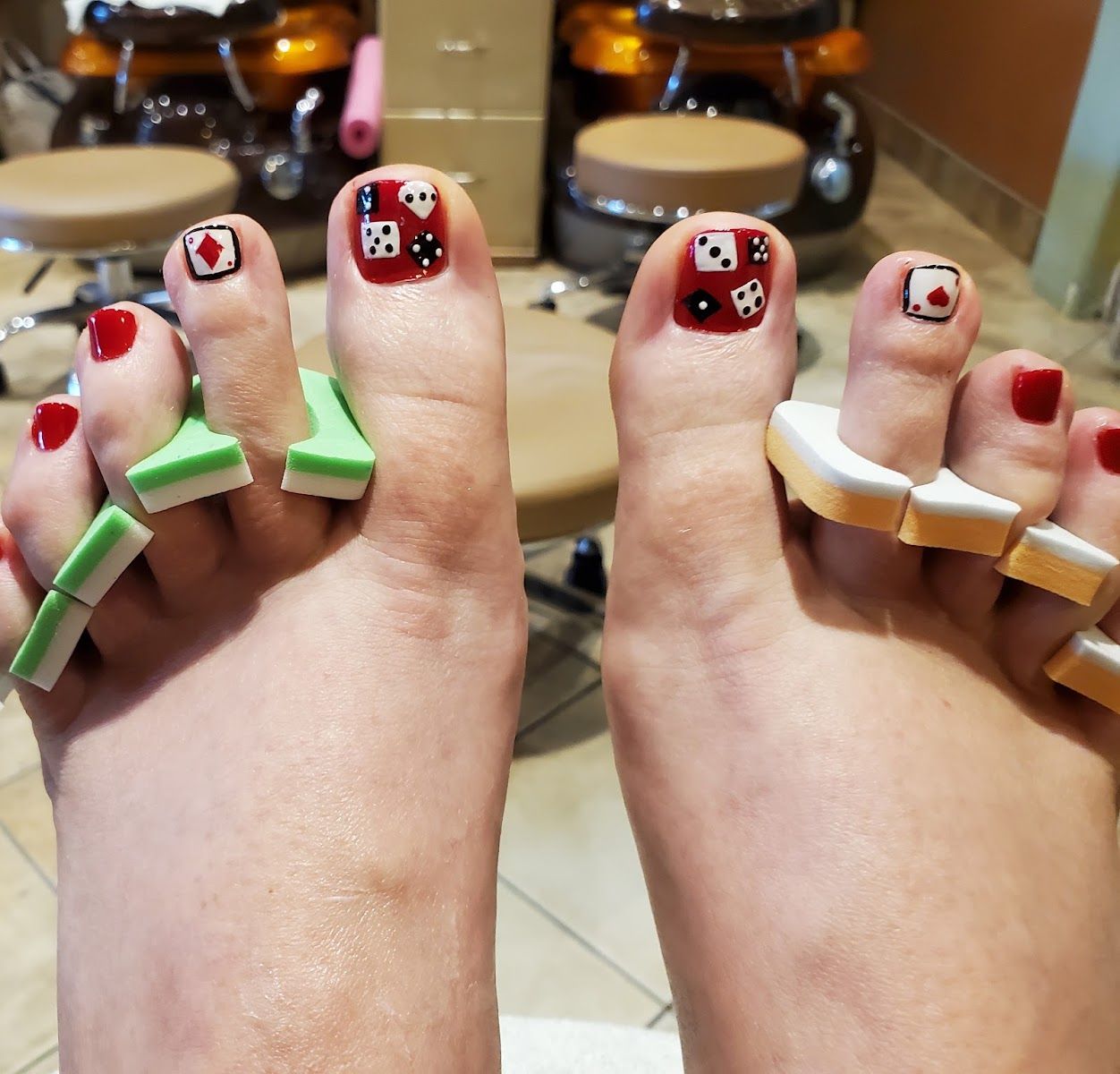 Pedicure with red toes and playing card art in the salon's pedicure chairs
