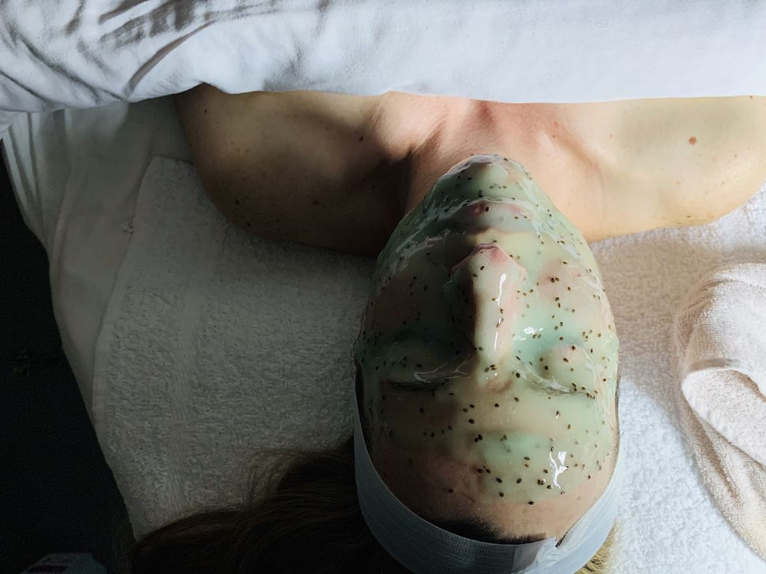 Green botanical mask applied during a facial