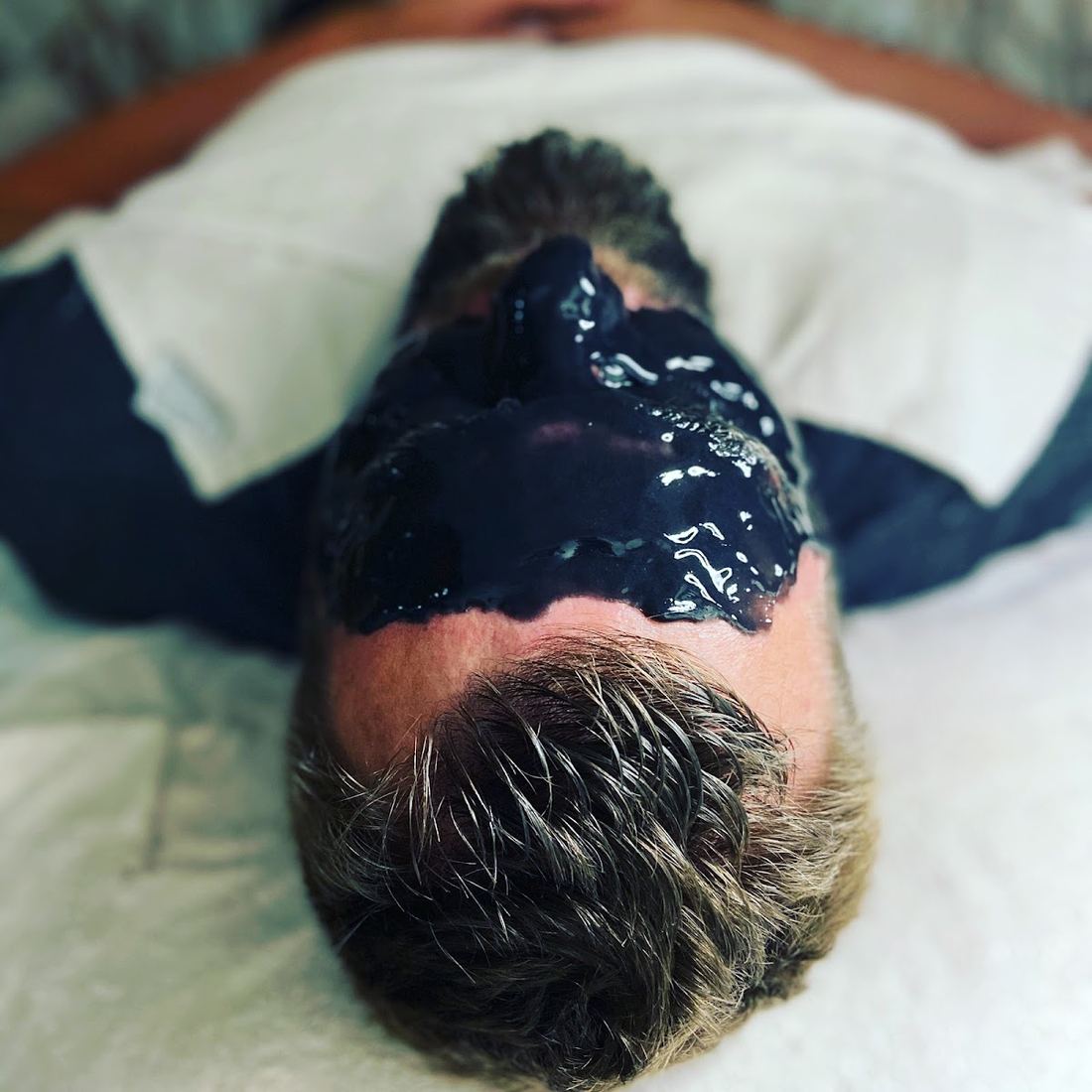 Dark charcoal mask applied to a client's face