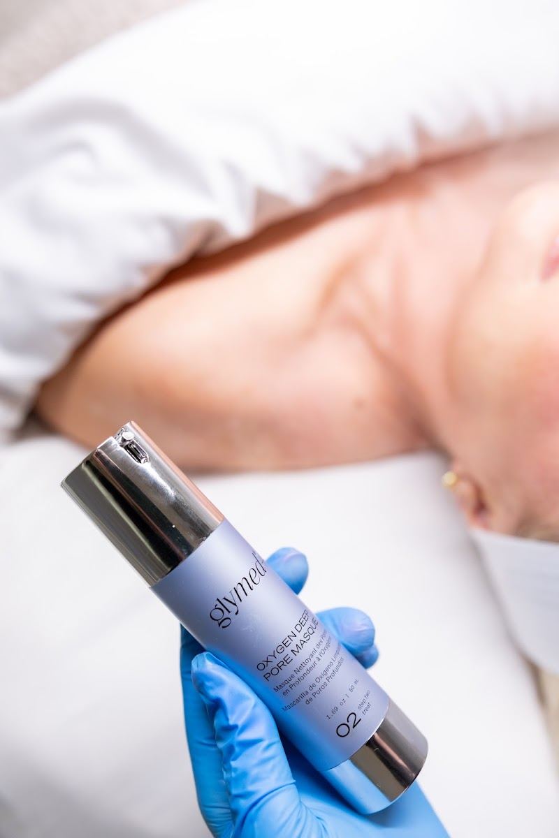 Gloved hand holding a skincare serum bottle beside a client