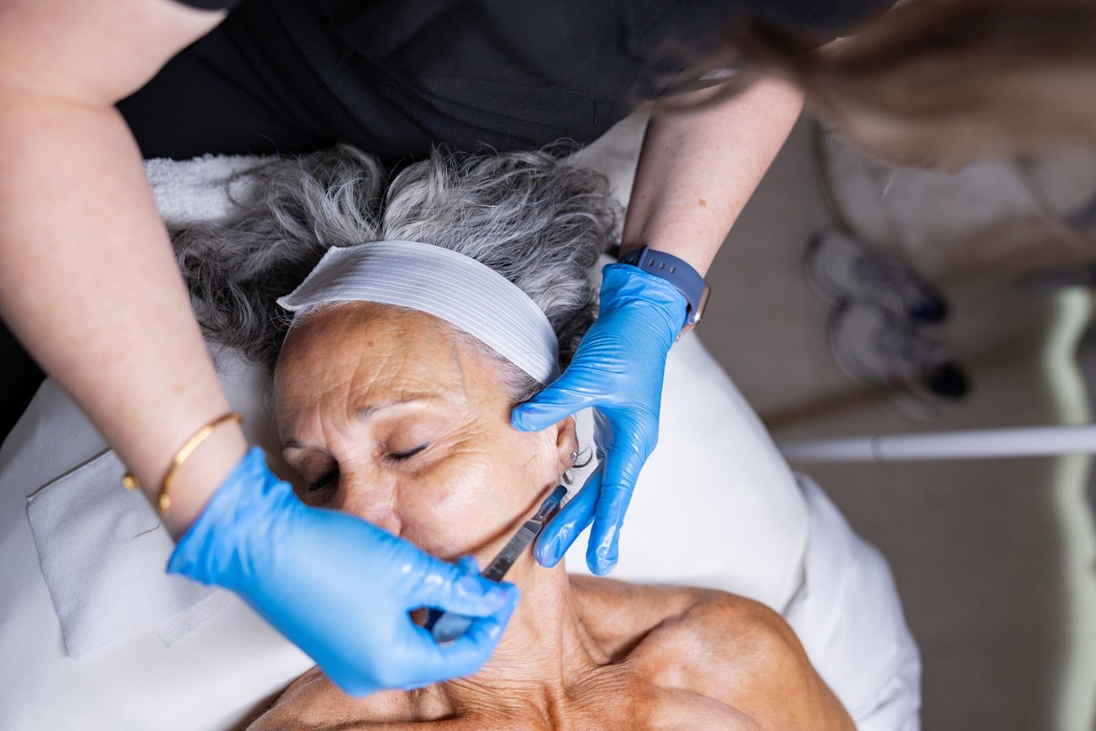 Gloved hands working on a client's face during a facial treatment