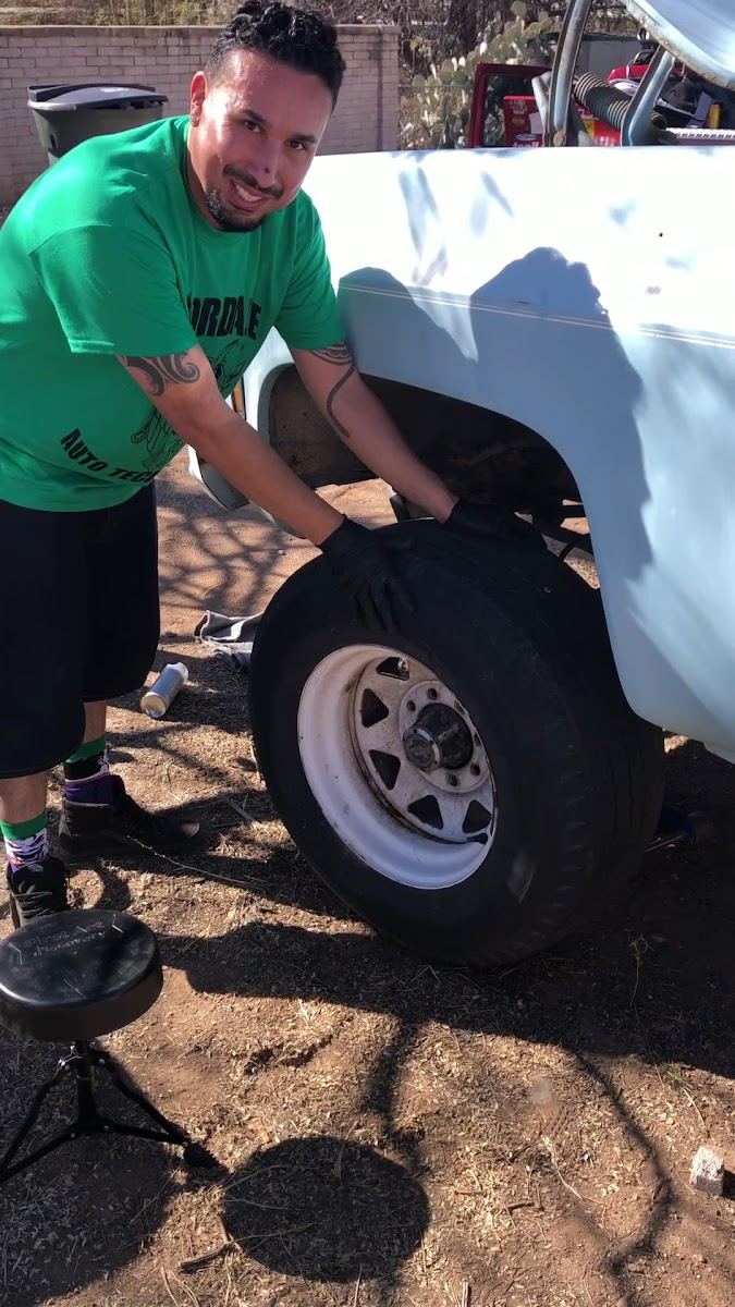 Smiling mechanic holding a tire next to a white truck