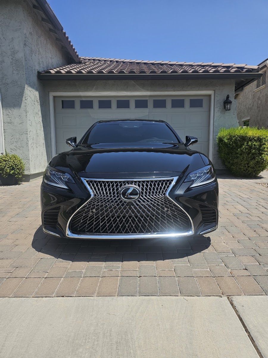 Black luxury sedan with tinted windows in front of a garage