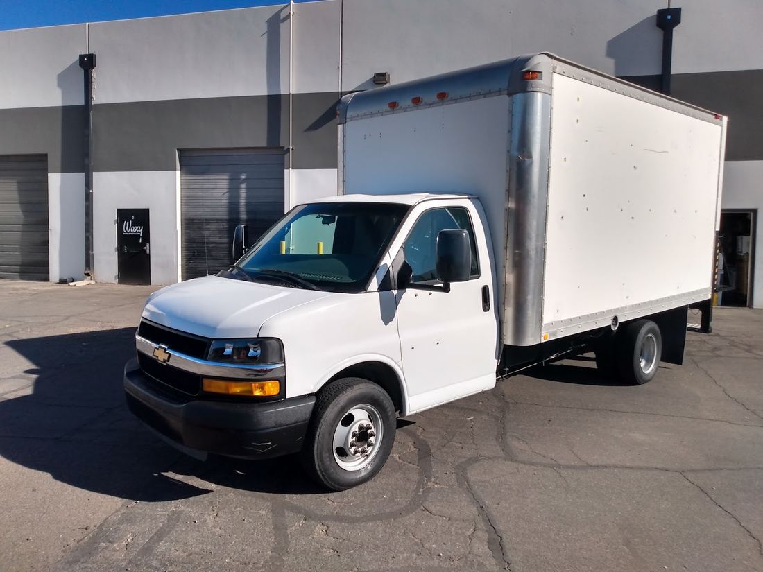 White box truck parked outside the shop