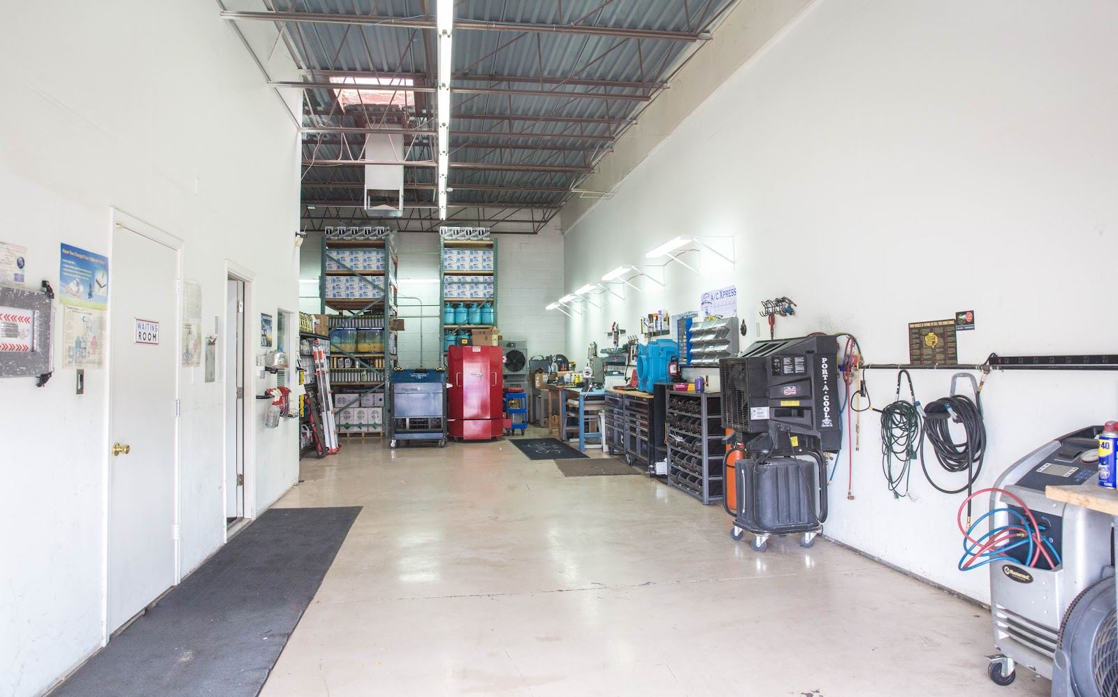 Inside the Auto A/C Xpress service bay with A/C equipment along the wall
