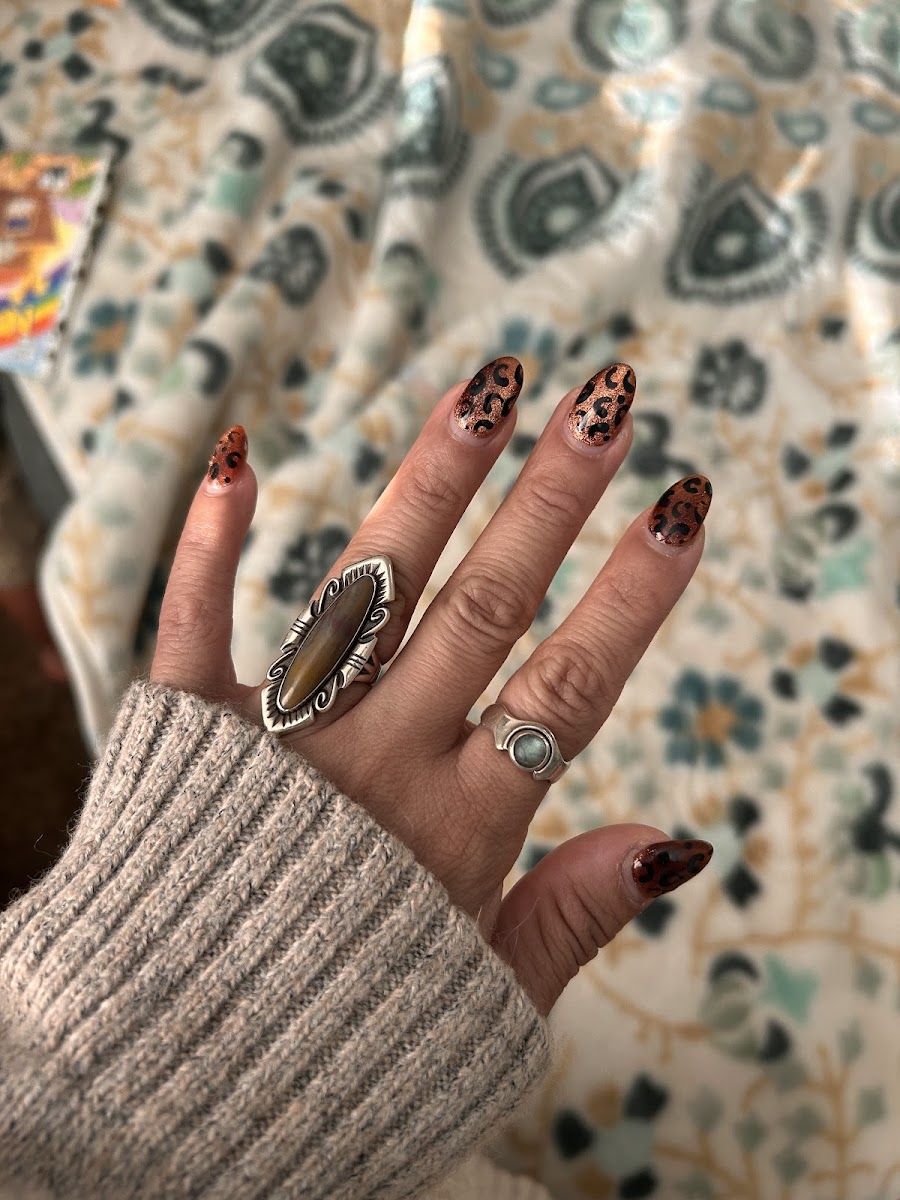 Dark almond nails with hand-painted detail and a turquoise ring
