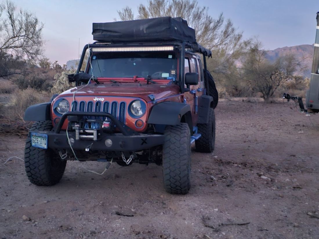 Red Jeep Wrangler with roof tent parked in the desert