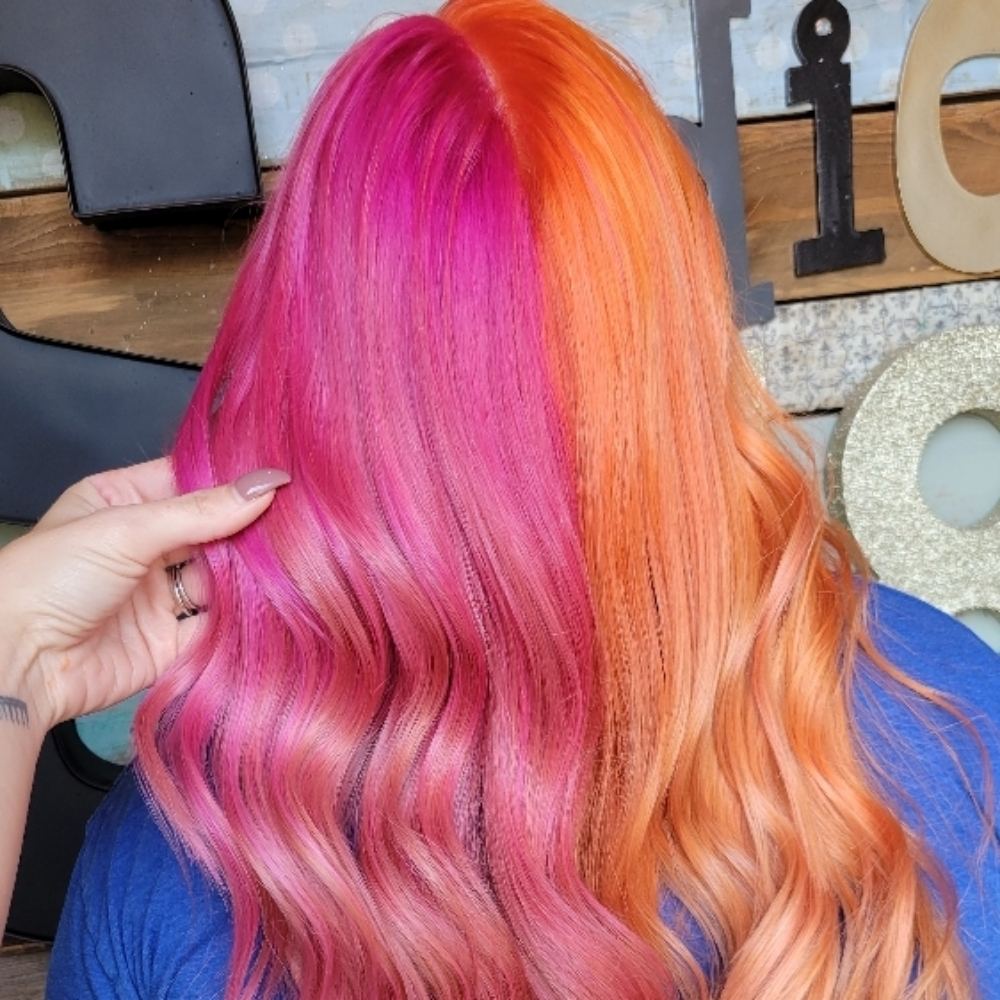 Long hair split down the middle, vivid pink on one side and bright orange on the other