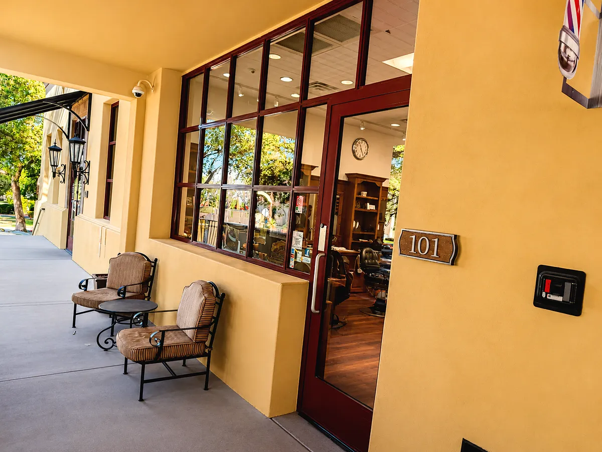 The shaded porch outside Suite 101: ochre stucco, a dark red door, wicker chairs and iron lanterns