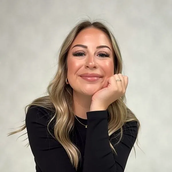 Rebecca smiling, chin resting on her hand, in a black top