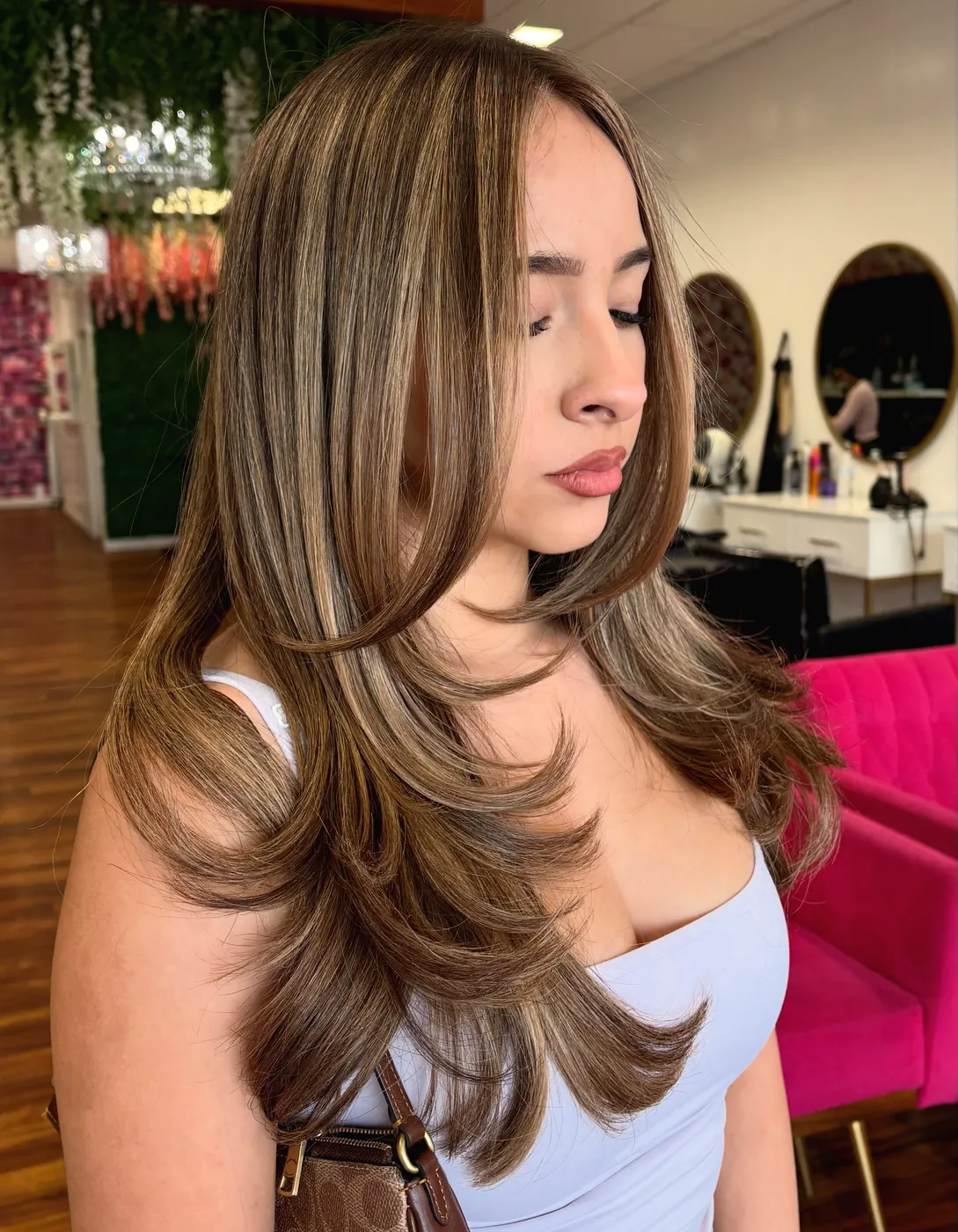 Brown balayage with face framing layers, in the salon with round mirrors behind