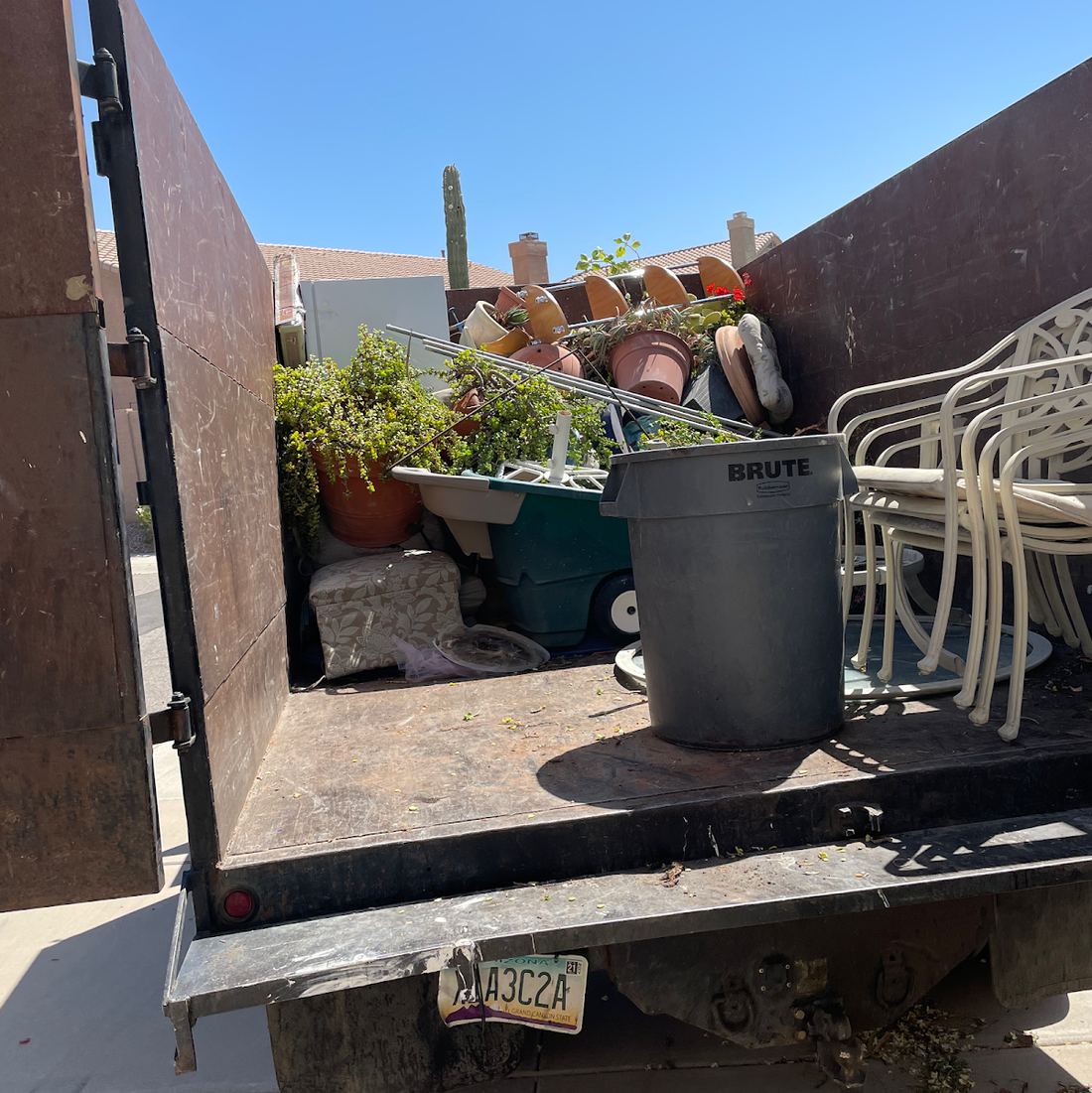 Patio chairs, potted plants and a trash can loaded in the truck bed