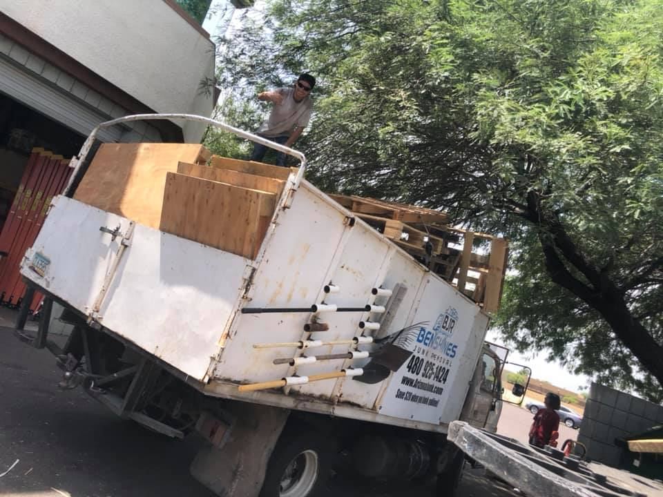 Truck loaded with lumber and debris beside a house