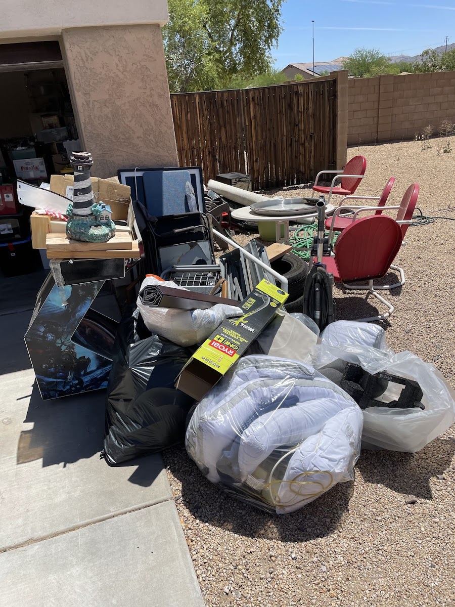 A pile of household junk, chairs and bags waiting by a garage