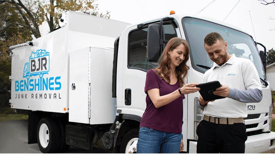 Benshines Junk Removal box truck with two team members reviewing a job on a tablet