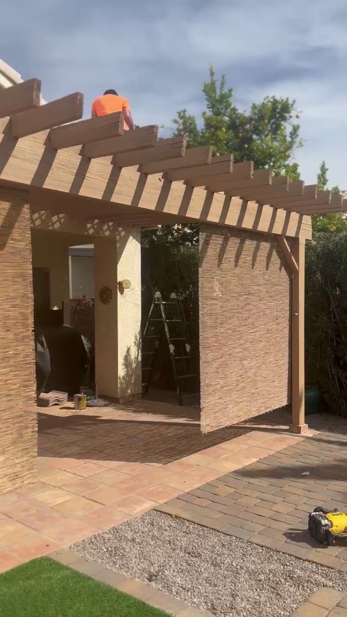 Backyard patio with a wood pergola and stone pavers