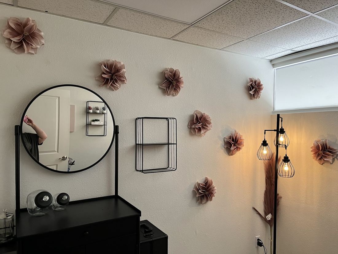 Round mirror and vanity beside pink paper flowers