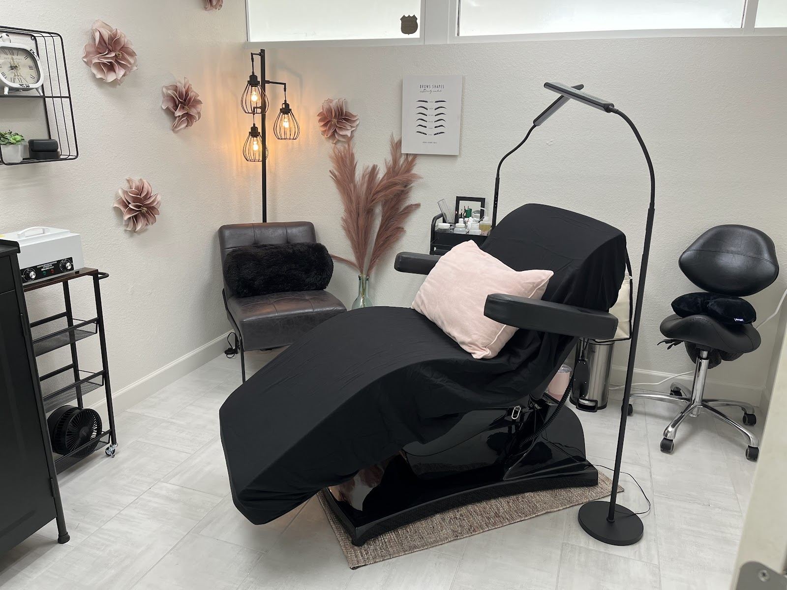 Treatment room with black reclining chair, blush pillow and paper flowers on the wall