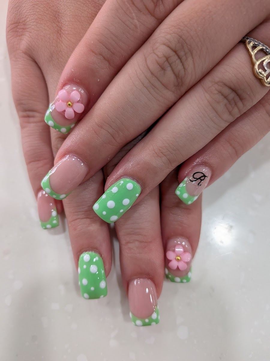 Green polka dot nails with a pink 3D flower and initial accent