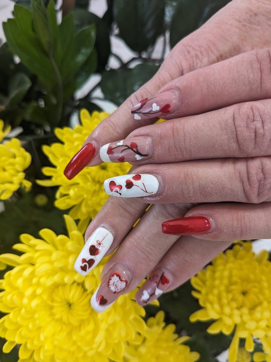 Red and white heart nail art over bright yellow chrysanthemums