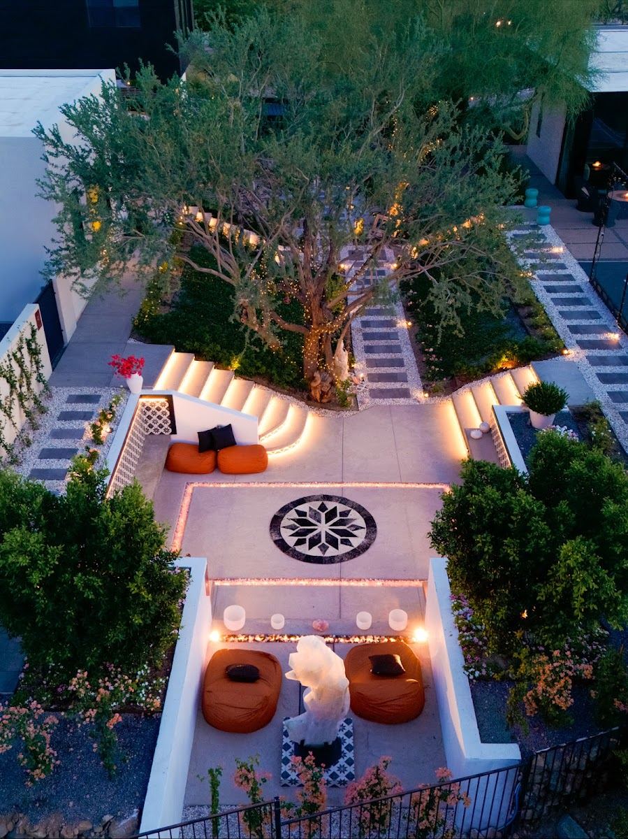 Lit courtyard with paver walkways, inlaid medallion, fire feature and lounge seating