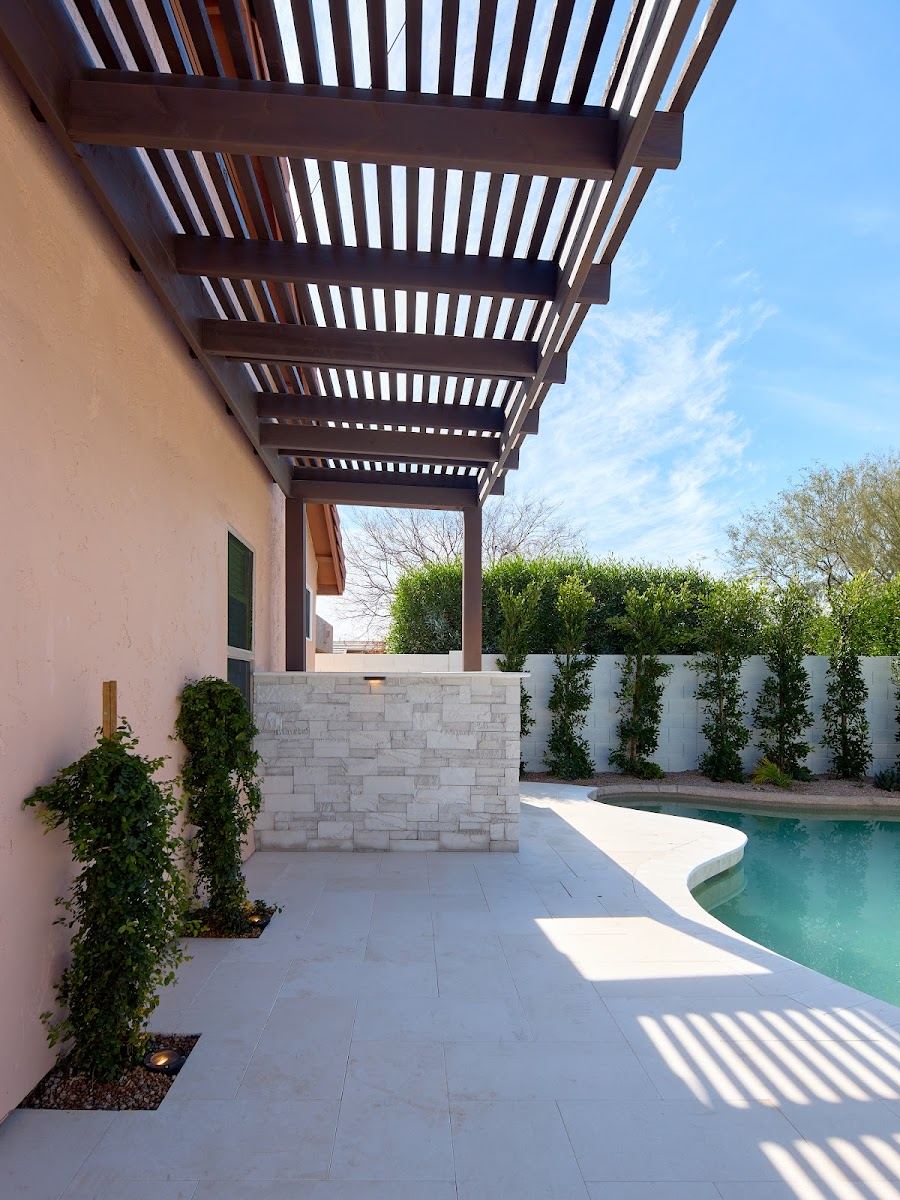 Pergola over a pale paver deck beside the pool
