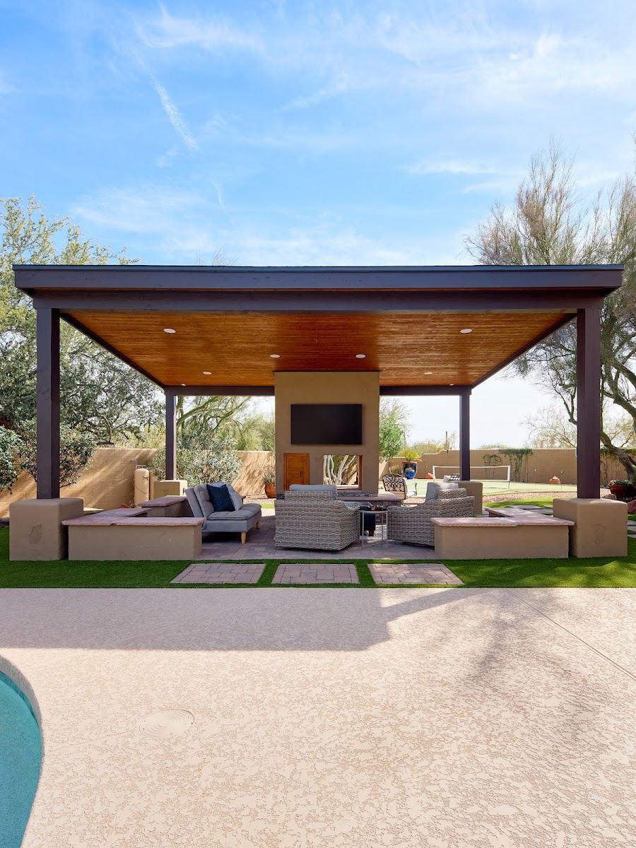 Covered outdoor living room with fireplace, seating and turf