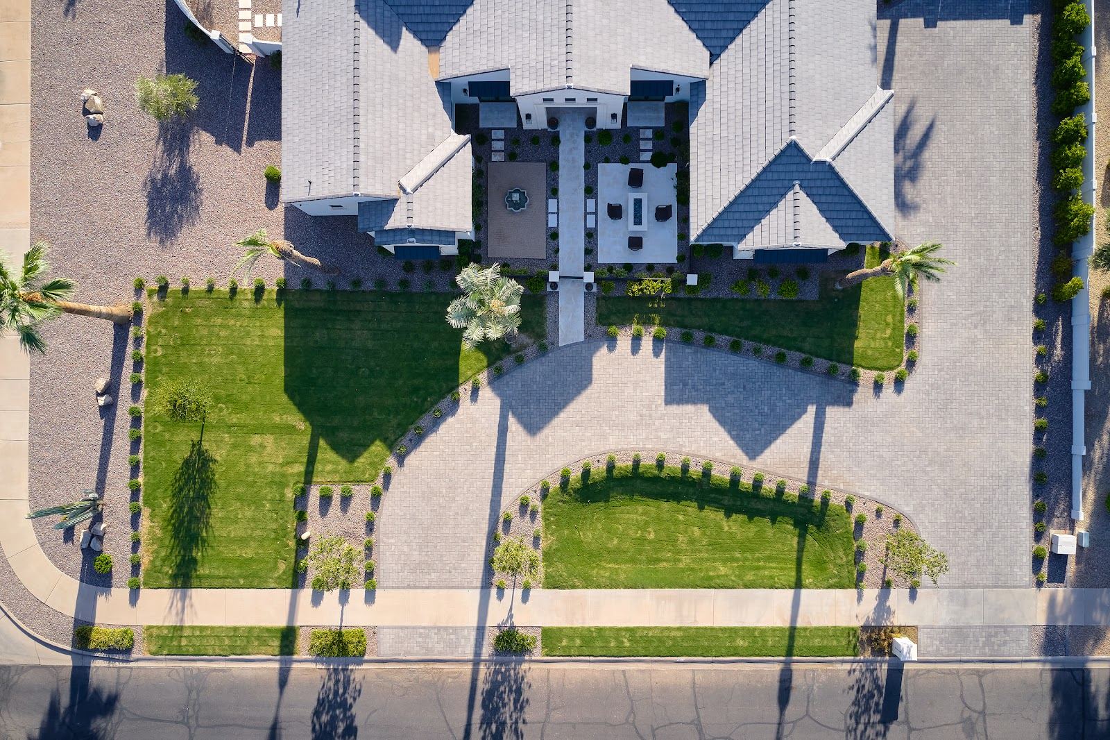 Aerial view of a finished front yard with curved turf beds, paver drive and palms