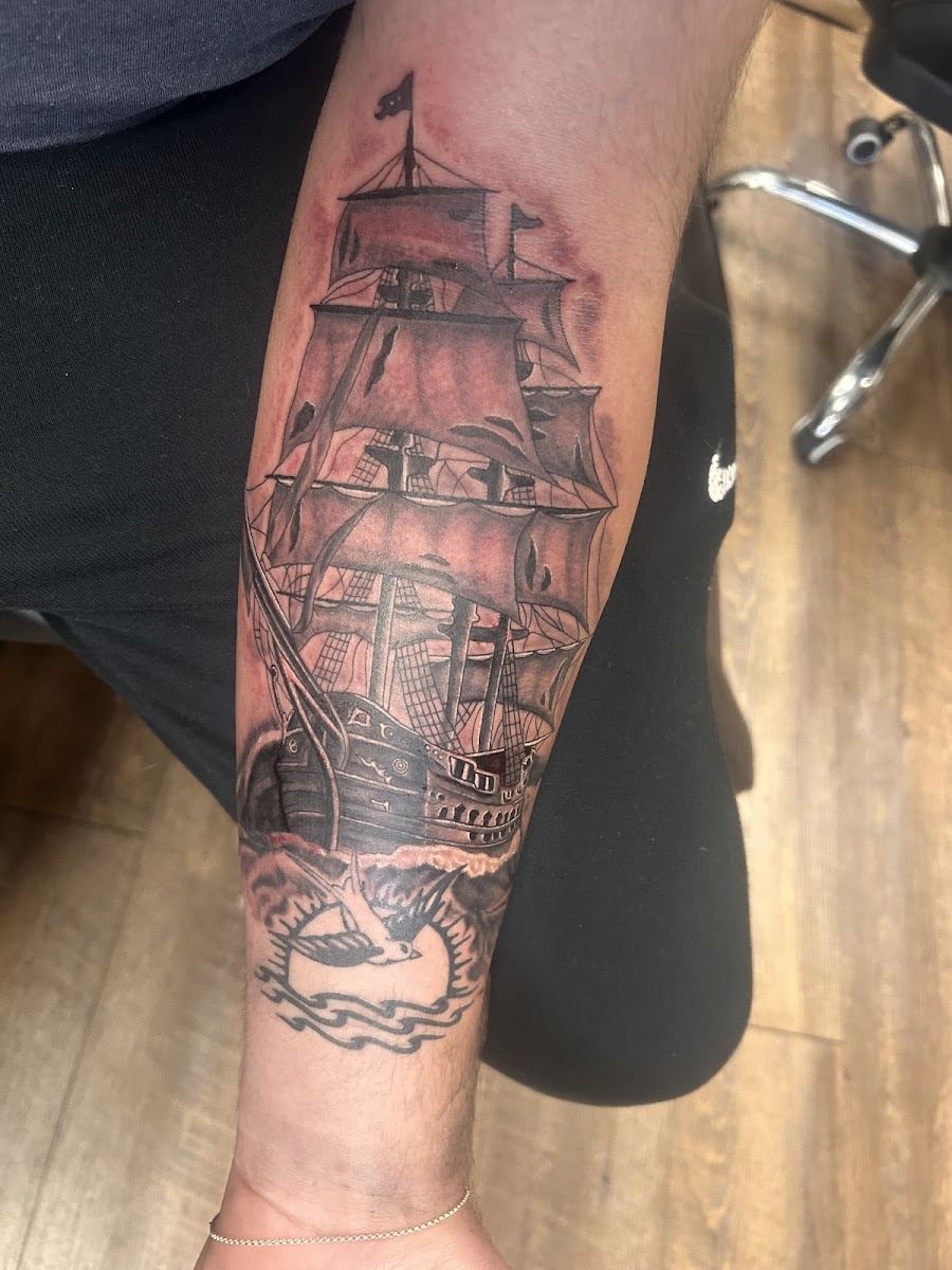 Black and grey tall ship tattoo on a forearm