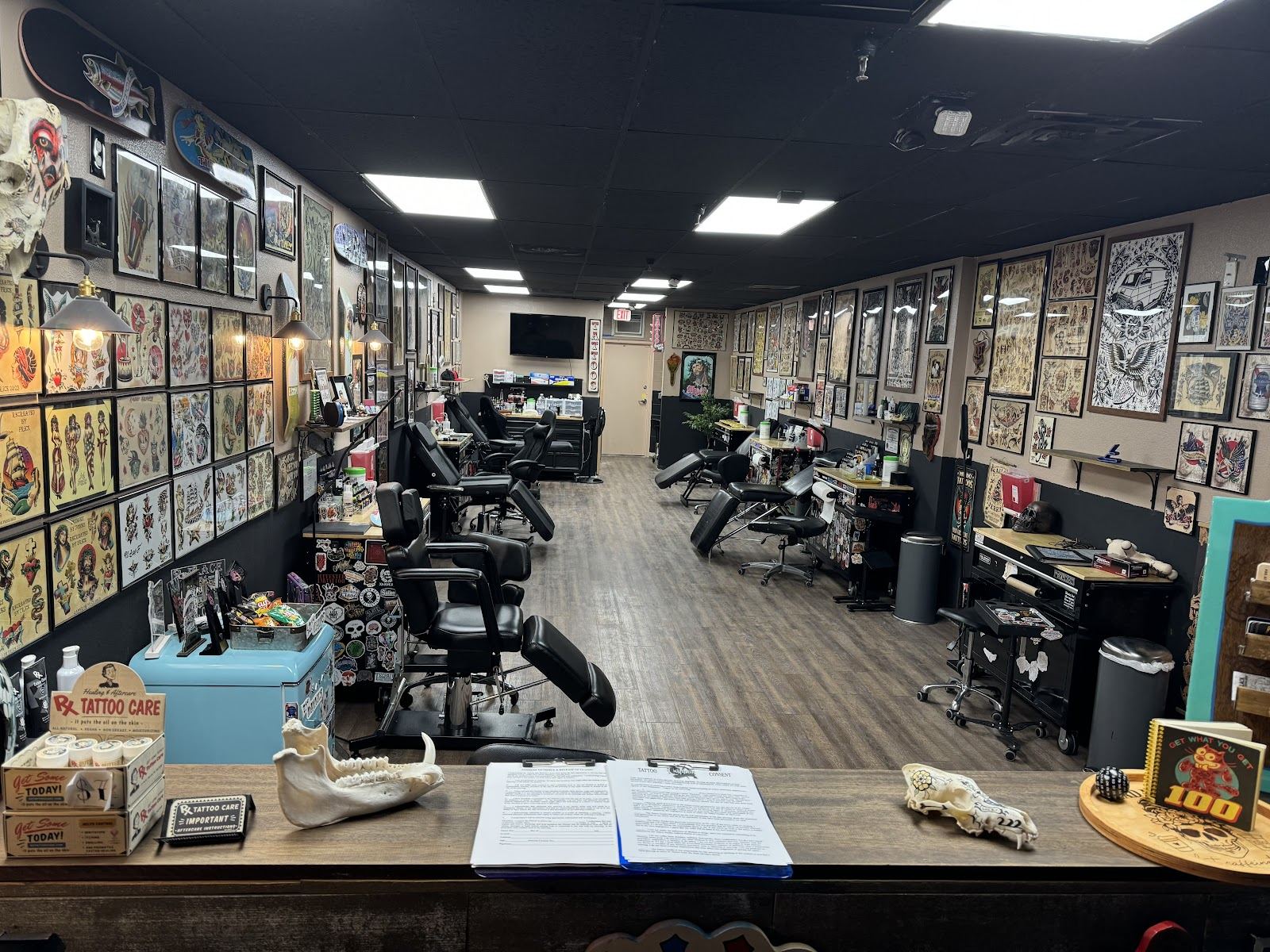 Inside Captain Tattoo Art Collective: tattoo stations under walls of framed flash