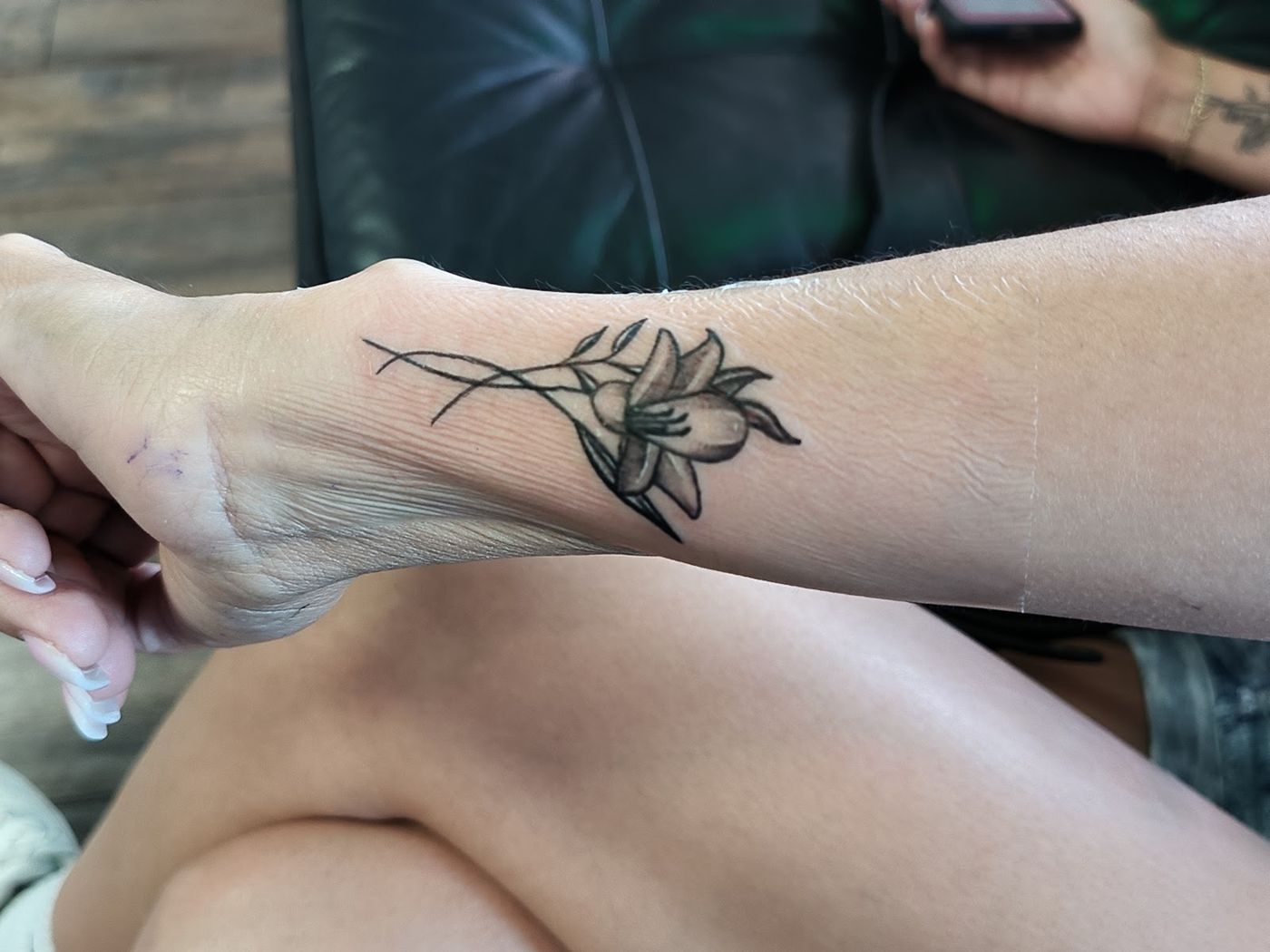 Fine line flower tattoo on a forearm