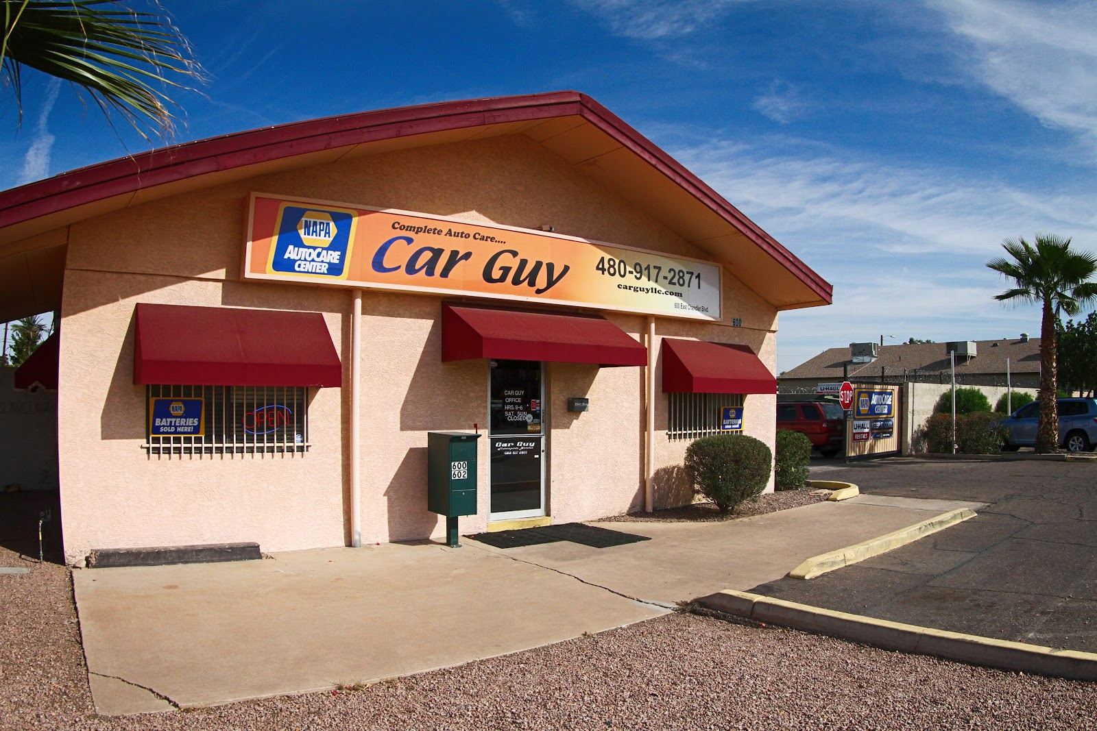 The Car Guy shop building with its blue and orange sign and red awnings