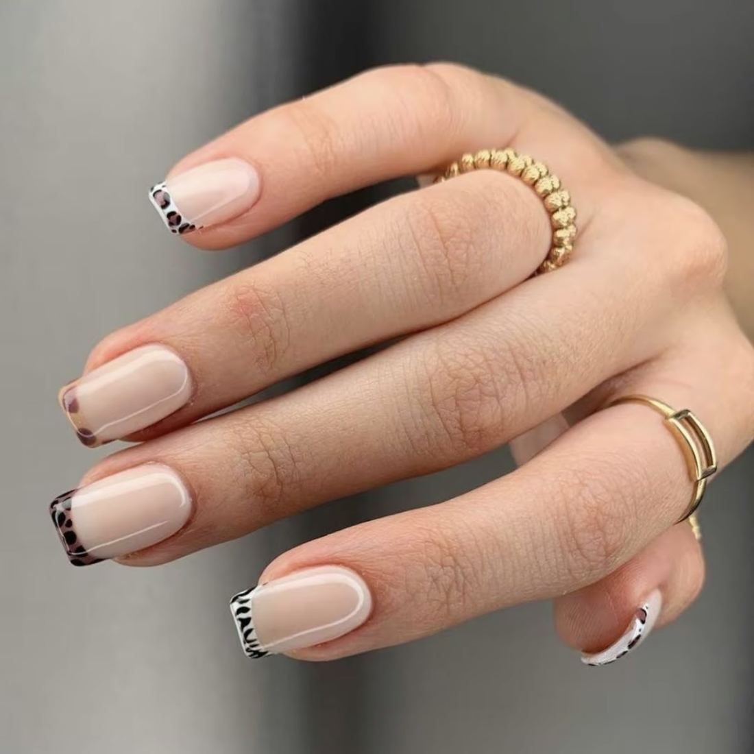 Natural nude nails with black and white animal print French tips