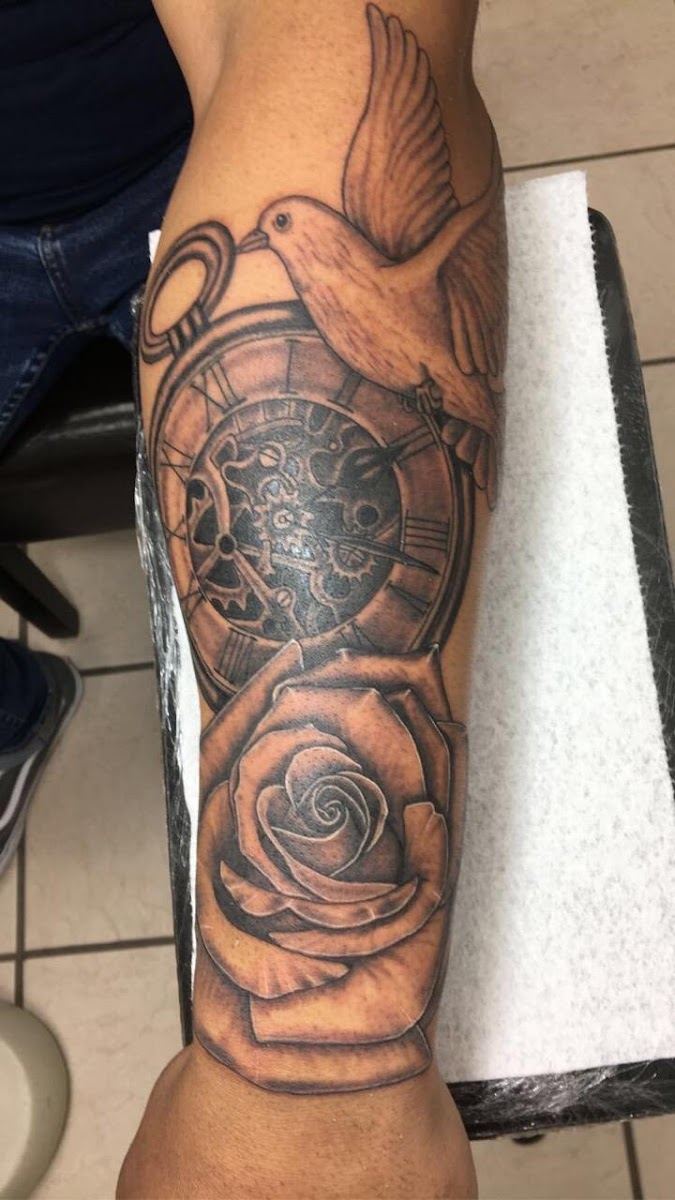 Forearm tattoo with a dove, compass and shaded rose in black and grey
