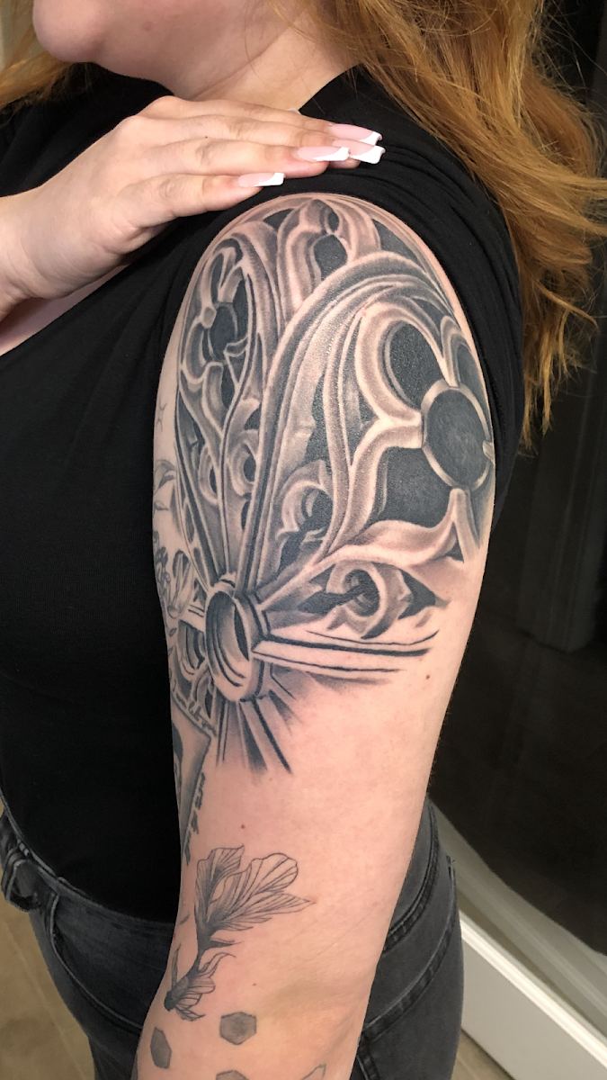Ornamental black and grey tattoo on an upper arm and shoulder