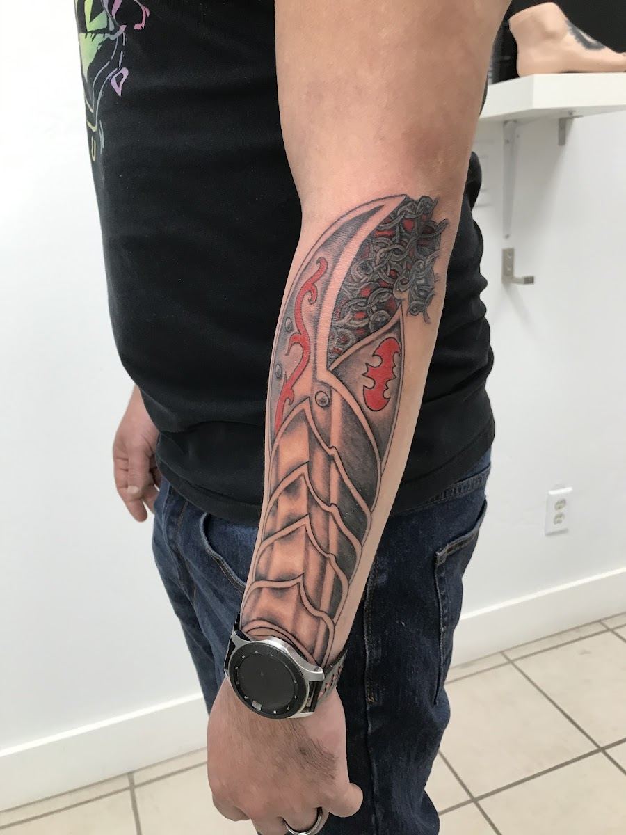 Detailed forearm tattoo in black and grey with a touch of red