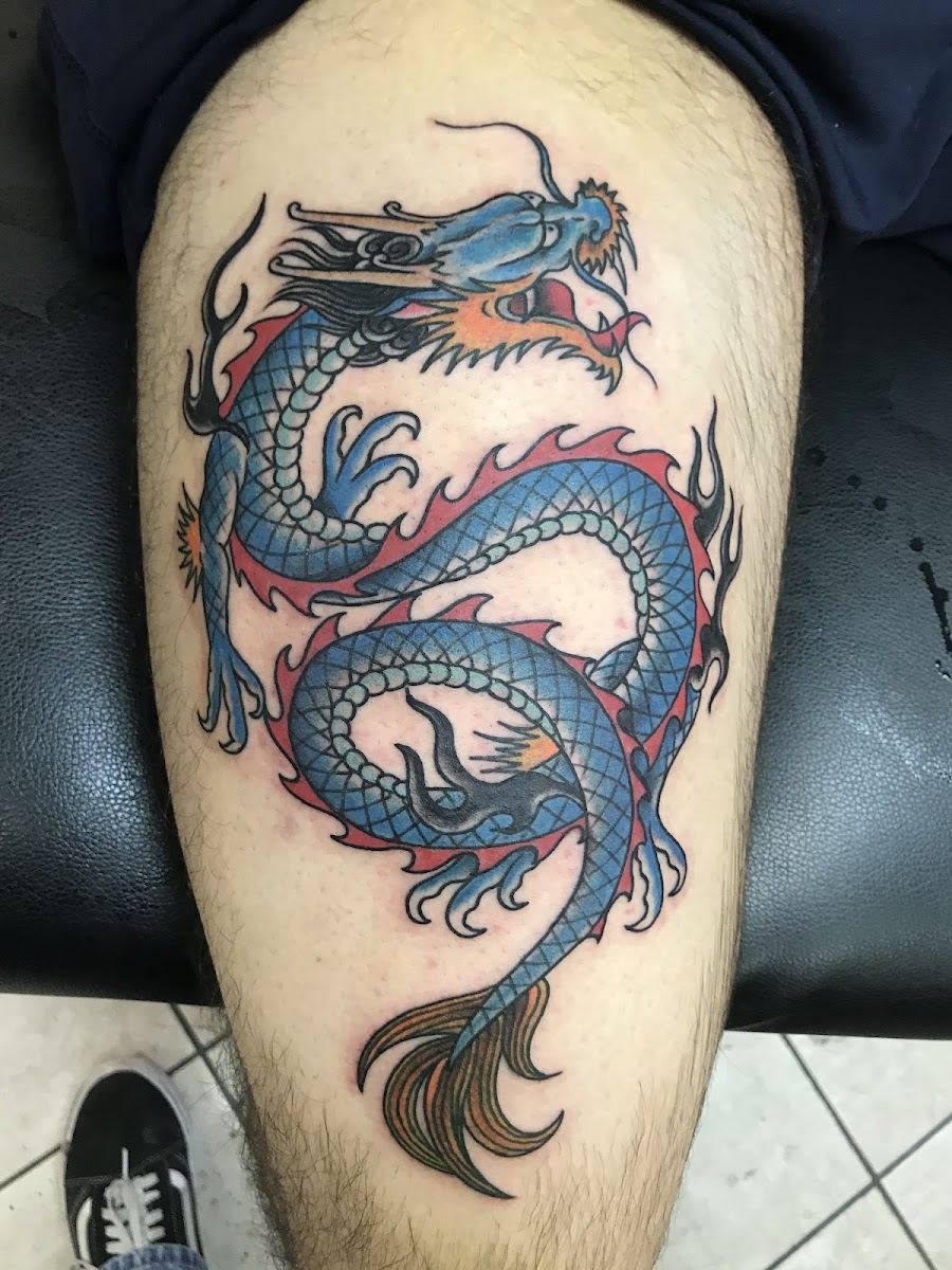Blue Eastern dragon tattoo coiling down a thigh
