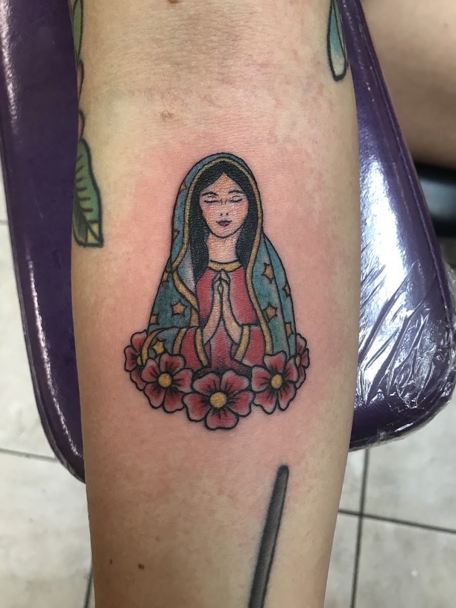 Small Virgin of Guadalupe tattoo with roses on a forearm