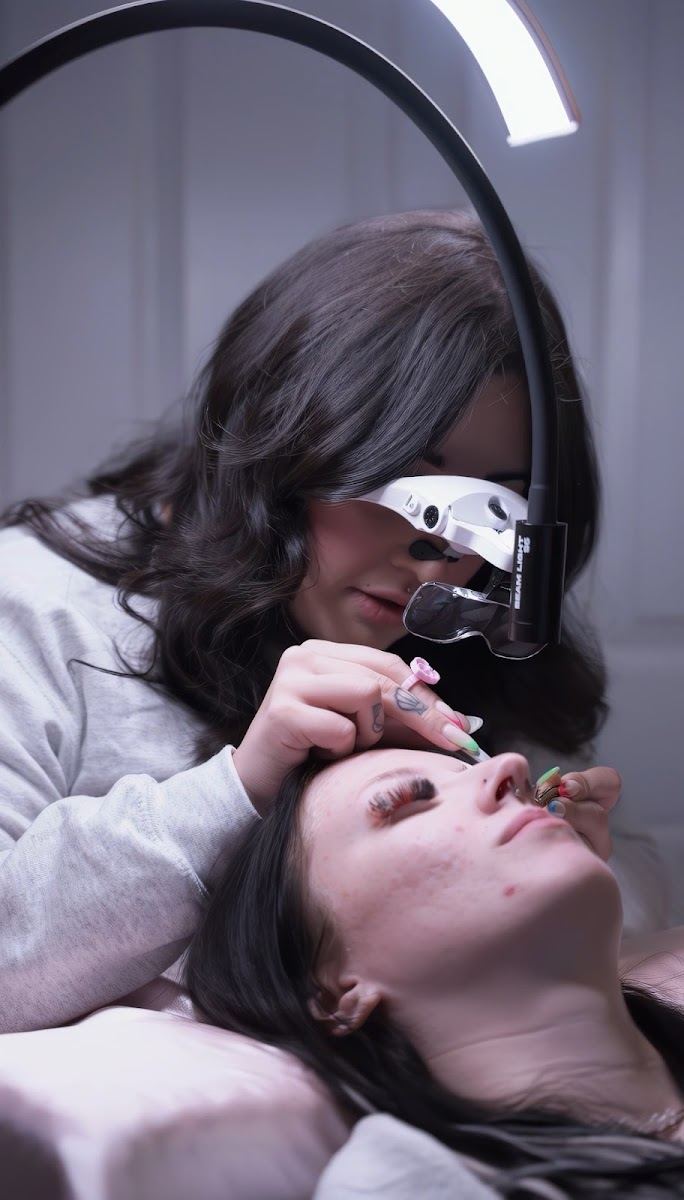 Danae applying lash extensions under a ring light