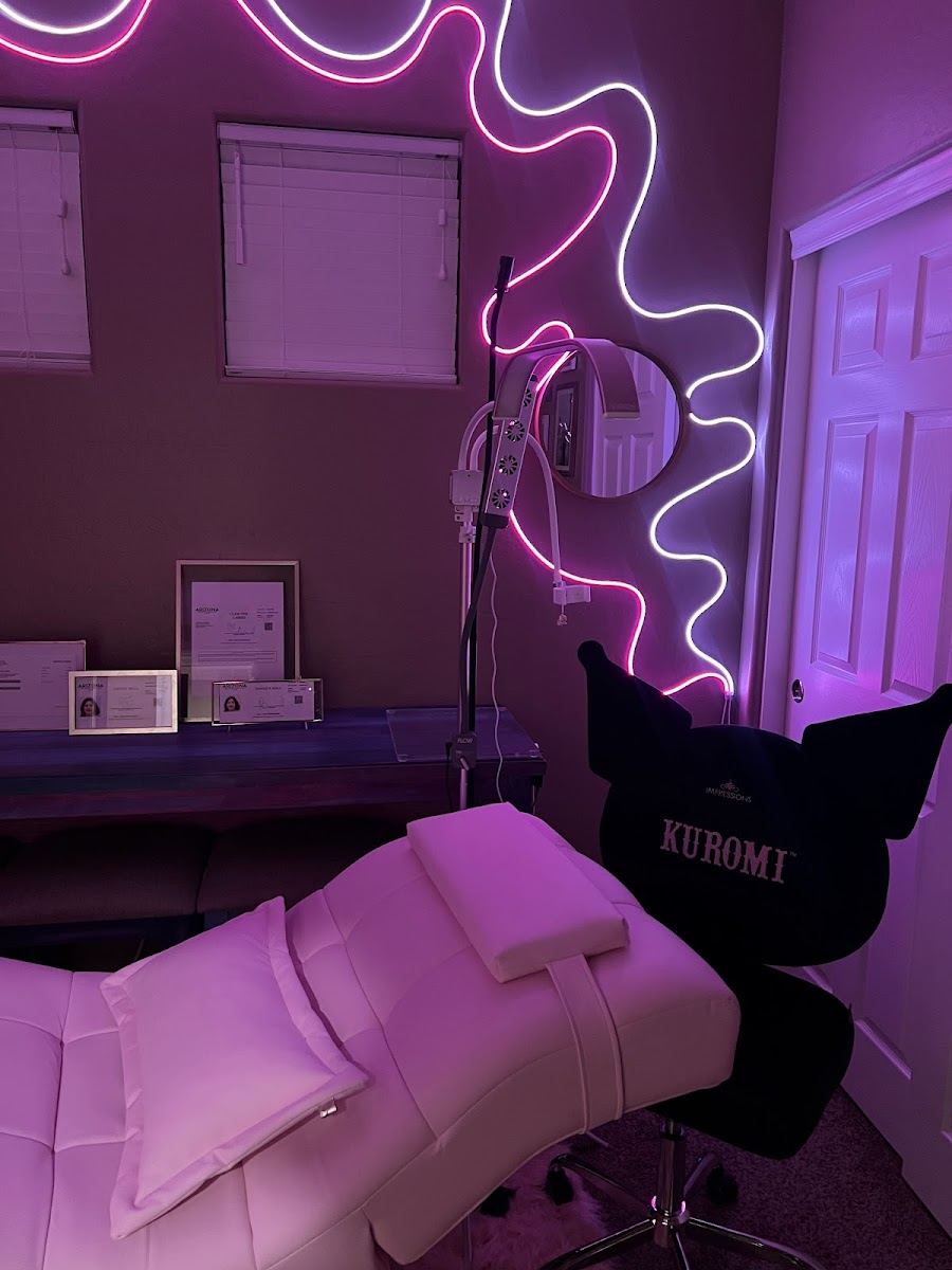 The Claw-ver Lashes studio with a wavy pink neon light and lash bed