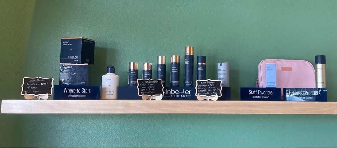 Skincare products displayed on a shelf against the sage wall