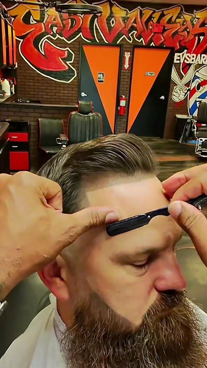 Barber lining up a client's hairline with a razor