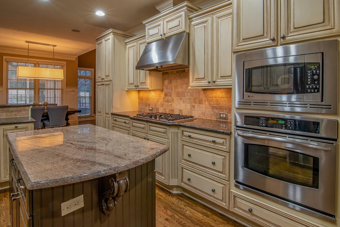 Cream kitchen with a granite island and stainless ovens