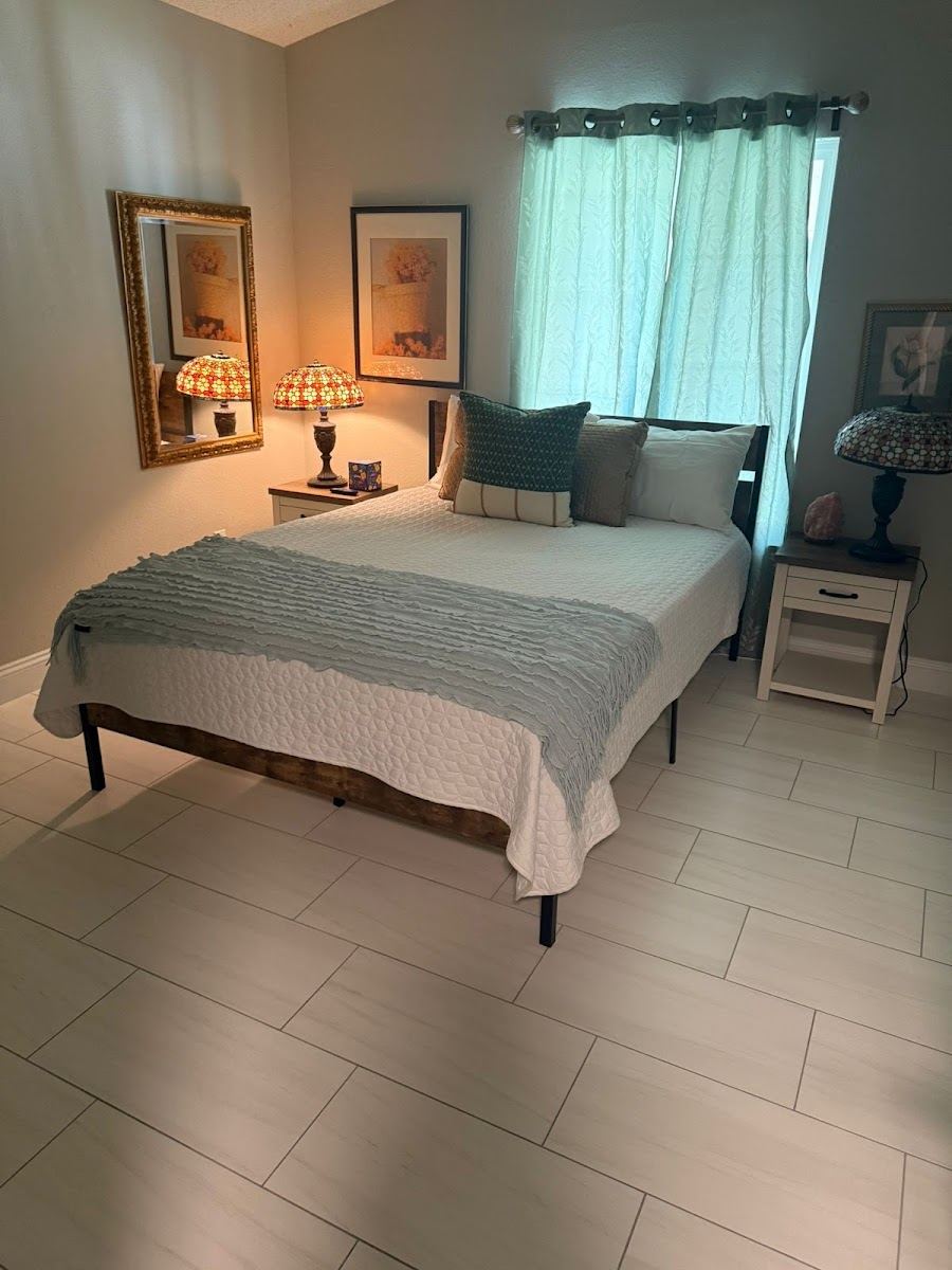 Tidy bedroom with a made bed and clean tile floor