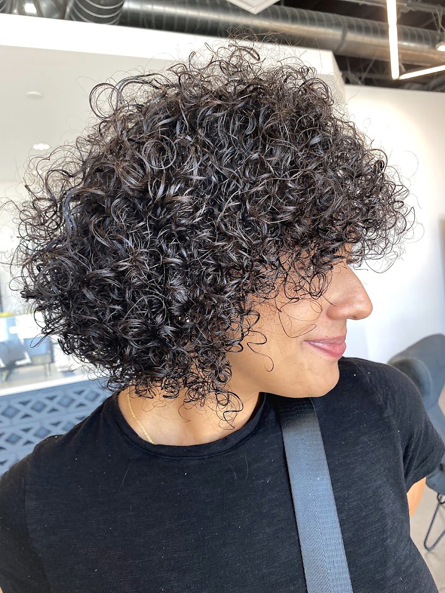 Client in profile with a short, rounded shape of tight defined curls
