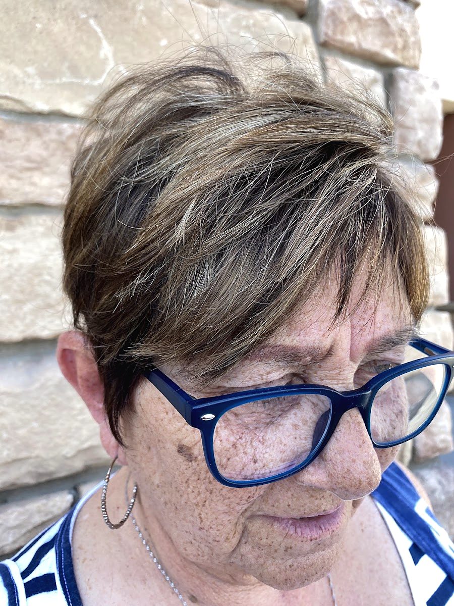 A client in blue glasses with a short, feathered cut with soft highlights