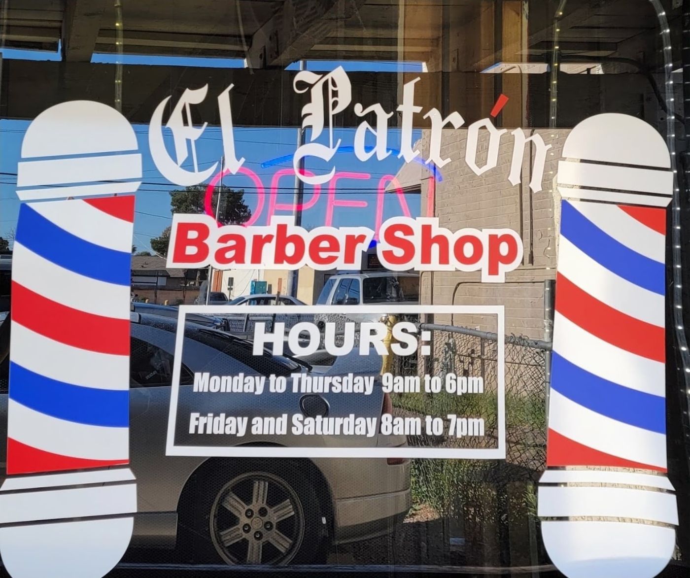 El Patrón Barber Shop window lettering with barber poles and posted hours